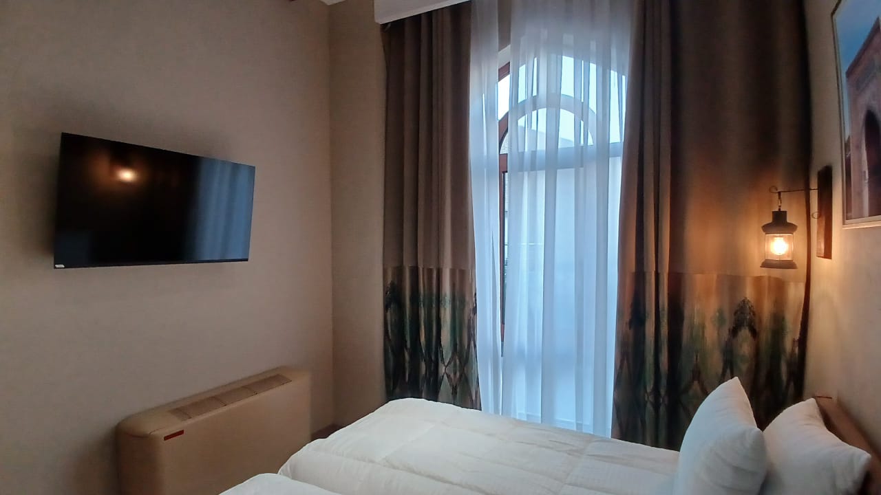Warm guest room with queen bed and arched window